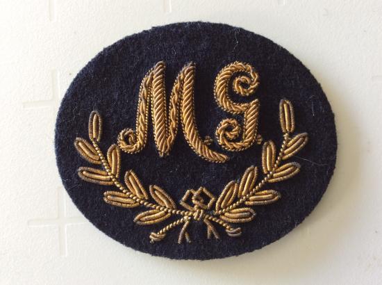 Gradia Militaria - M.G ( Machine Gun) good bullion on dark blue wool trade badge