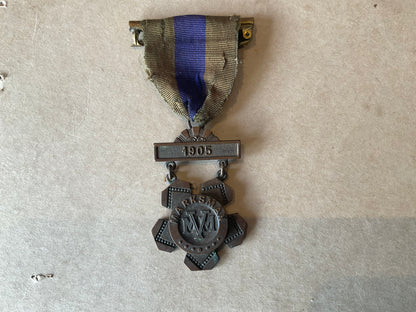 Bronze Massachusetts Volunteer Militia marksman’s medal dated 1905, retaining its original two‑colour suspension ribbon.