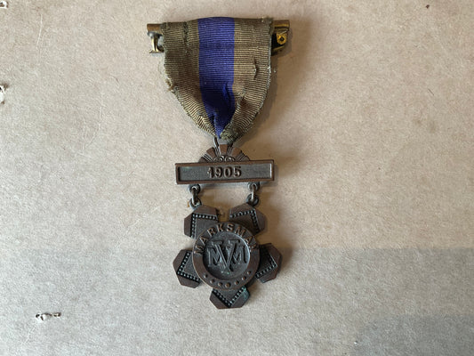 Bronze Massachusetts Volunteer Militia marksman’s medal dated 1905, retaining its original two‑colour suspension ribbon.