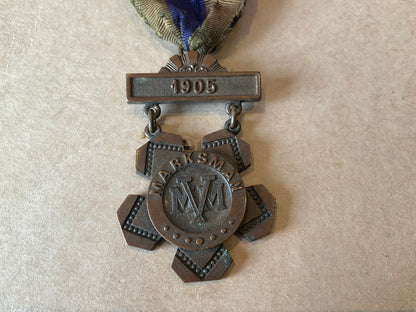 Bronze Massachusetts Volunteer Militia marksman’s medal dated 1905, retaining its original two‑colour suspension ribbon.